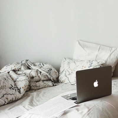 白色床上的银色macbook